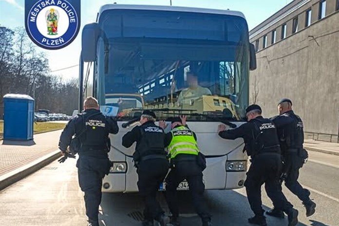 Strážníci tlačící autobus